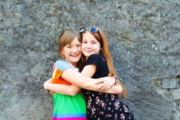 Two funny girl friends playing outdoors, wearing dresses