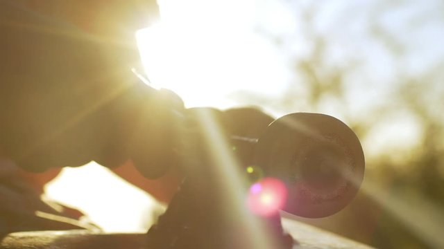 Close up footage in slowmotion with sun flare. Skateboarder tightening suspencion bolt