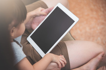 Asian little kid girl and her family sitting and using digital tablet together.