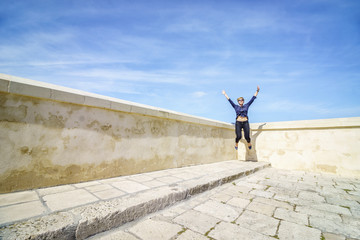 Happy woman jumping in the corner of the terrace
