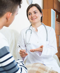 Doctor examinating teen boy with quinsy at home