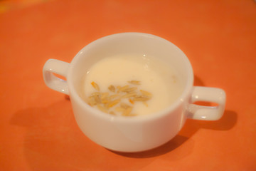 Mushroom cream soup in white bowl isolated on yellow orange table as background