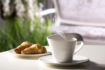 White cup with steam on white table on interior background