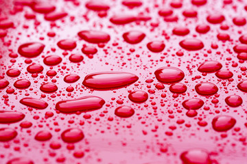 Water droplets on a red metal surface. Bubbly background or wallpaper.