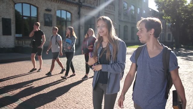 Two happy students walking on university campus