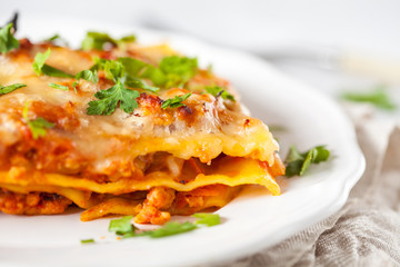 Piece of traditional Italian meat lasagna on a white plate.