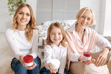 Obraz na płótnie Canvas Girl, mother and grandmother holding jars of cream
