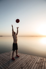 Fototapeta na wymiar Concentrated young sportsman make sport exercises with ball