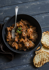 Easy peri-peri chicken livers in a cast iron skillet on a dark background, top view. Simple rustic lunch