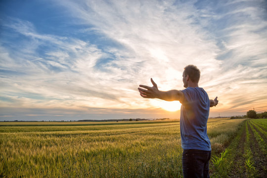 Man Standing In An Open Field At Sunset With Open Arms - Embracing Nature