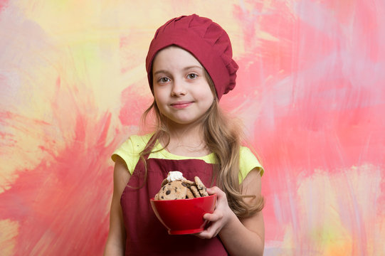 child, small girl in red chef hat, apron with chocolate cookies