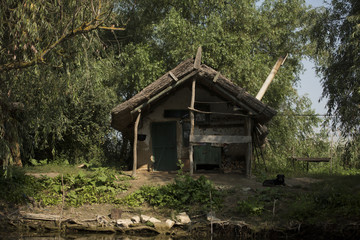 Fototapeta na wymiar Old wooden house on a channel in Danube Delta, Romania, in a sunny summer day