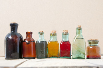 Many antique glass bottles with colored liquids close up. For the pharmacy, oil, cosmetics.