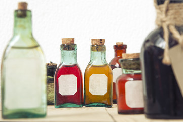 Mock up of small glass antique bottles with a colored liquid with label close up. For the pharmacy, oil, cosmetics, spices. Selective focus.