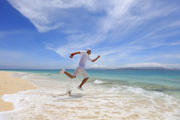 南国の美しいビーチを走る笑顔の男性
