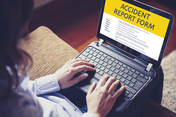 Woman fill in an accident report form with a laptop by internet. - 159434519
