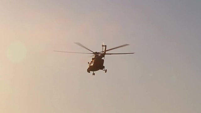 hd video of silhouette of military helicopter is flying to the sunset