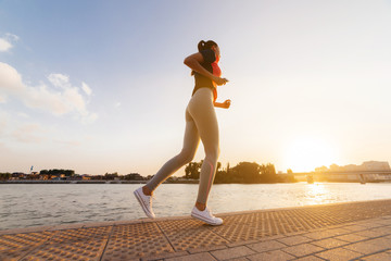 Woman runner jogging near river,listening music