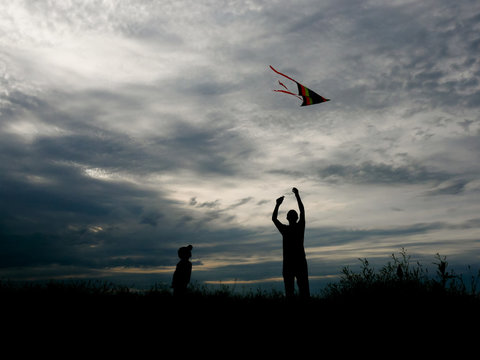 father and son flying a kite at sunset