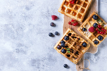Homemade square belgian waffles with fresh ripe berries blueberry, raspberry, red currant served...