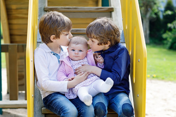 Fototapeta na wymiar Two little happy kid boys with newborn baby girl, cute sister.