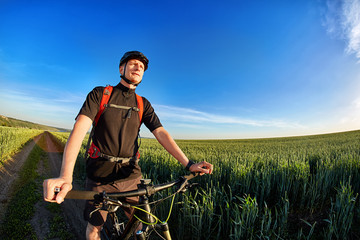 Fototapeta na wymiar Portrait of the cyclist with mountain bike on a background of blue sky with clouds.