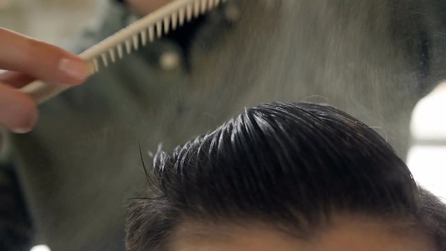 Hairdresser using a hairstyle technique on a man. Slow motion.
