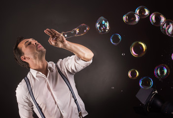 Artist blowing many soap bubbles from his hands. Bubble show studio concept.