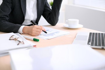 Business woman  is sitting at the table and working in  white colored office.