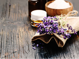 Obraz na płótnie Canvas Lavender spa ,bunch of lavender flowers , essential oil and salt on a black wooden background.