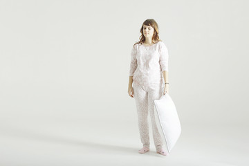 Fototapeta na wymiar girl standing in pajamas with a pillow white background