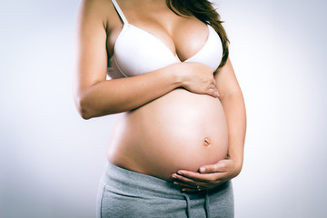 Belly tummy of pregnant woman on gray background