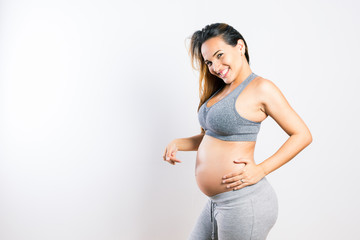 Beautiful pregnant latin woman pointing at her belly