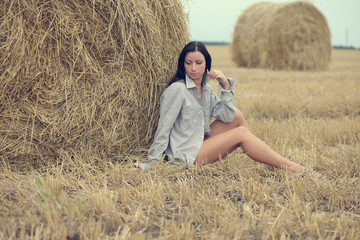 Naklejka na ściany i meble woman sitting in field with haystacks