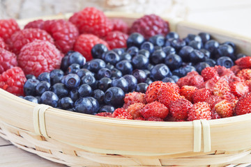 Wild berries in woven basket (wild strawberries, blueberries and raspberries)