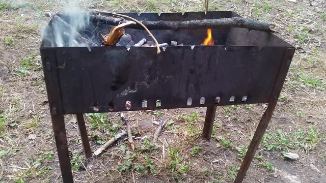 Rusty metal brazier for frying meat smokes in the forest