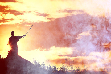 Naklejka na ściany i meble Silhouette of a warrior with a sword in the smoke of a mountain war