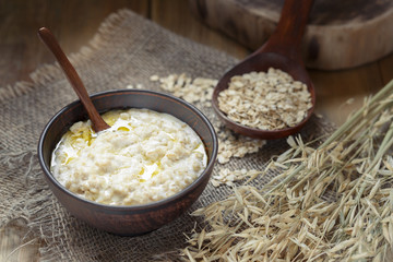 Oatmeal with butter. Oatmeal in a clay bowl on burlap, low key, close-up.