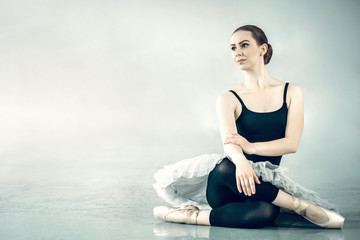 Fototapeta na wymiar Bellerina sitting on the floor in ballet studio