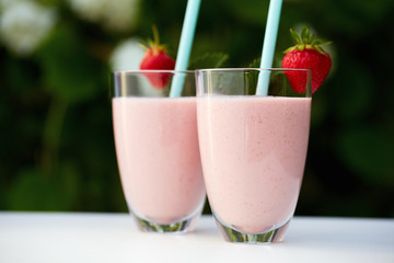 Glasses of fresh smoothie with strawberry on white table