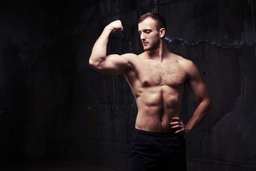 Shirtless man flexing muscles showing great relief of his arms and torso