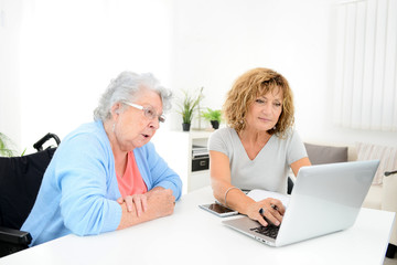 mature woman helping assisted elderly senior female with administrative procedures and paperwork on...