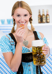 Nettes Mädchen isst Brezel und trinkt Bier