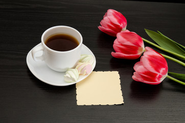 Fototapeta na wymiar Mug of coffee and marshmallows, clean postcard, three pink tulips. Black background.