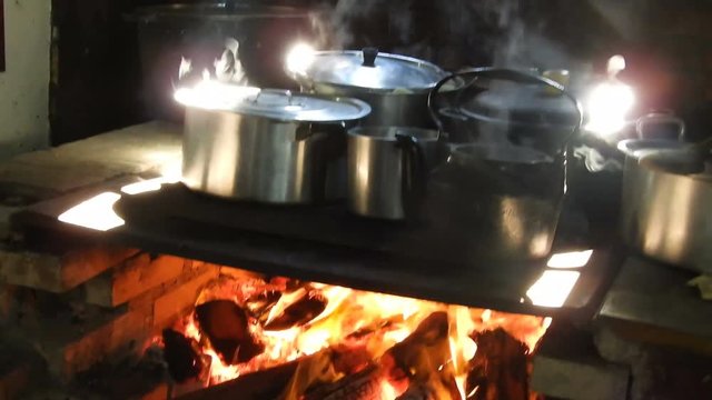 Rustic Brazilian farmhouse cooking. Large pans on large open fronted iron wood burning stove - pan between the pans and flames