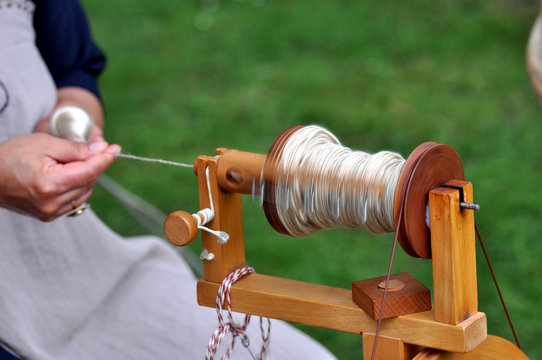 Eine Frau spinnt Seide am Spinnrad im Detail