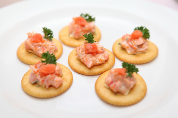 Cracker with fish eggs and salmon on white plate-selective focus