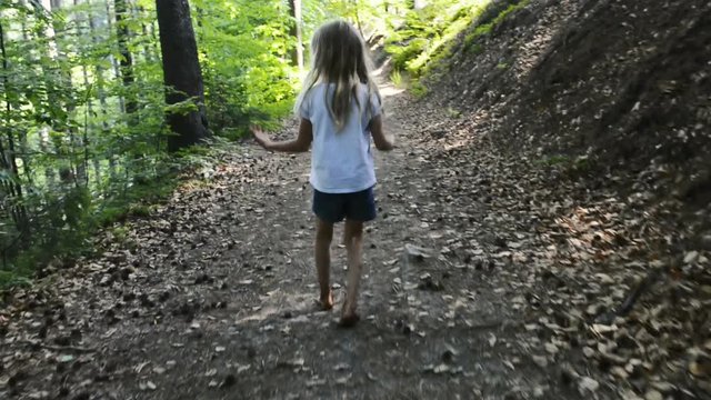 A girl walking barefoot on a forest path