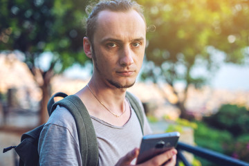 Fototapeta premium Man traveler with backpack looking at his smartphone on the background of nature and the mountains