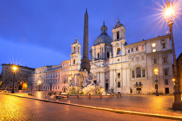 Fountain of the Four Rivers with an Egyptian obelisk and Sant Agnese Church on the famous Piazza Navona Square at night, Rome, Italy.